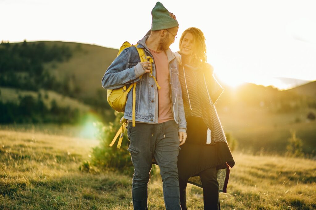 Couple of hikers walking along mountain grassy trail during a vacation